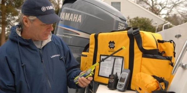 Man inspecting marine radio equipment by a boat engine.