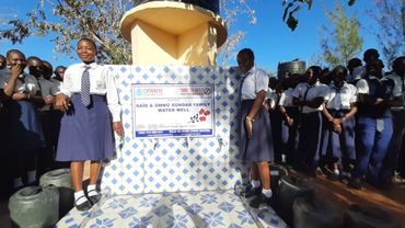 Drought in kenya: two girls smiling next to a charity borehole in Kenya