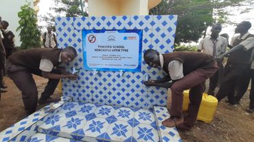 Drought in Kenya: two boys smiling next to a charity borehole