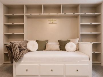 Cozy daybed with pillows and shelves.