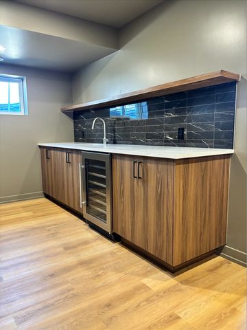 Modern kitchen counter with wood cabinets and black tile backsplash.