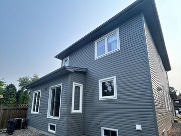 Two-story gray house with white-framed windows.