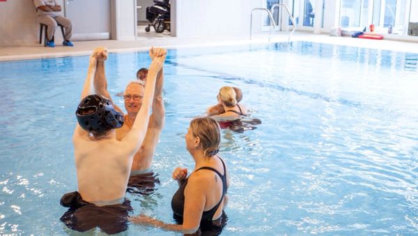 People enjoying a swimming pool session together indoors.
