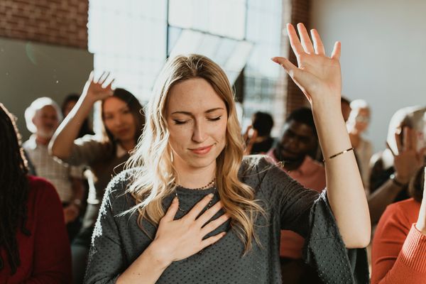 People with hands raised in what appears to be worship or prayer.