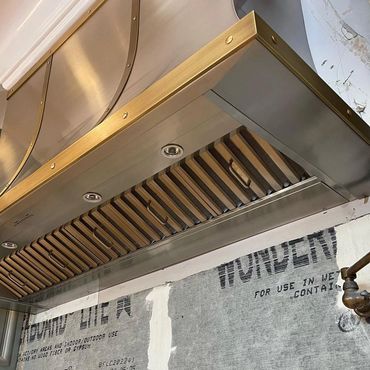 Hood #9667. Stainless steel kitchen hood with sweeping curved detail and clipped corners. 