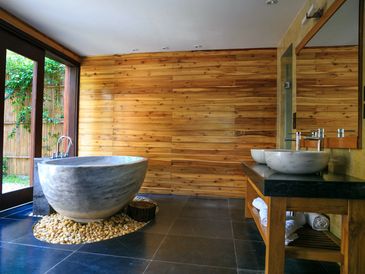 A bathroom with a wooden wall and rounded bathtub