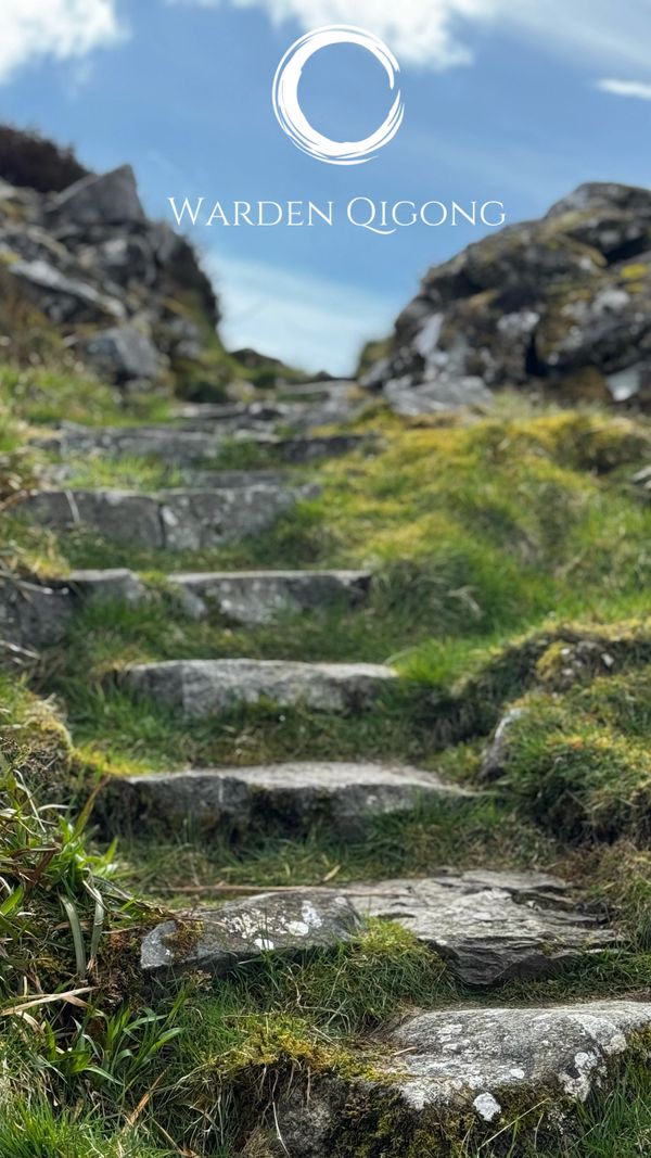 Stone steps leading up a grassy, rocky path under a blue sky with 'Warden Qigong' text.