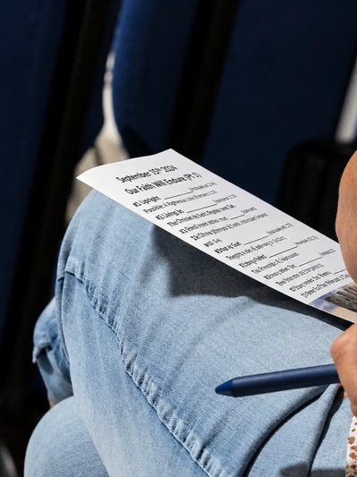 Person holding a printed agenda or schedule and a pen.