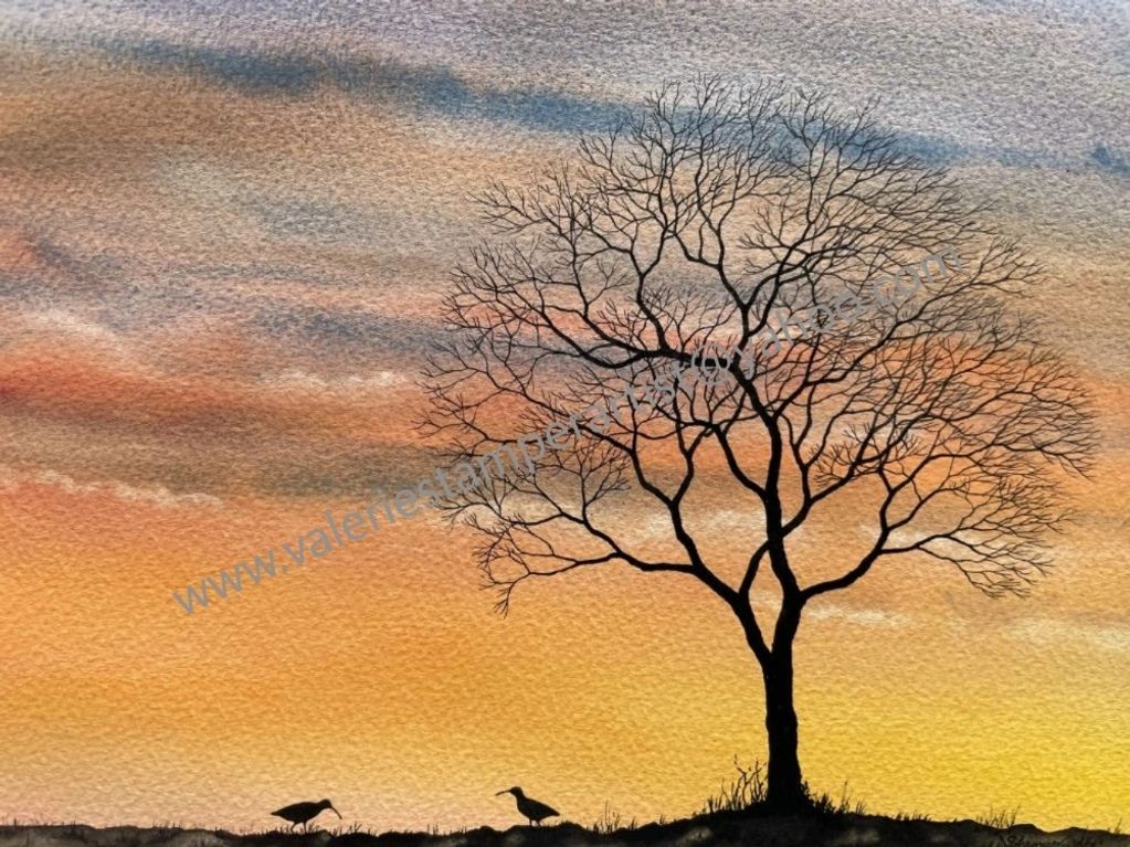 Silhouette of a bare tree and two birds at sunset with a textured sky.