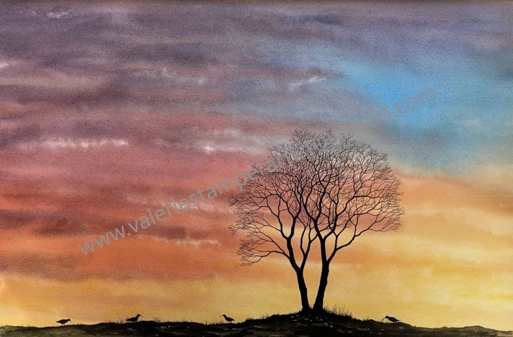 Silhouette of a tree and birds against a colorful sunset sky.