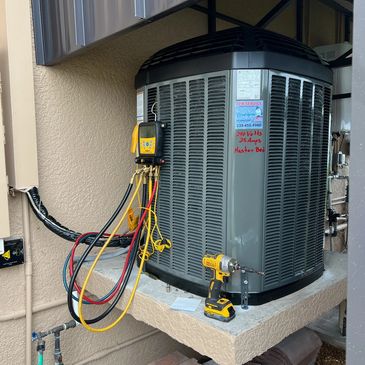 HVAC unit with diagnostic tools and a power drill on a concrete platform.