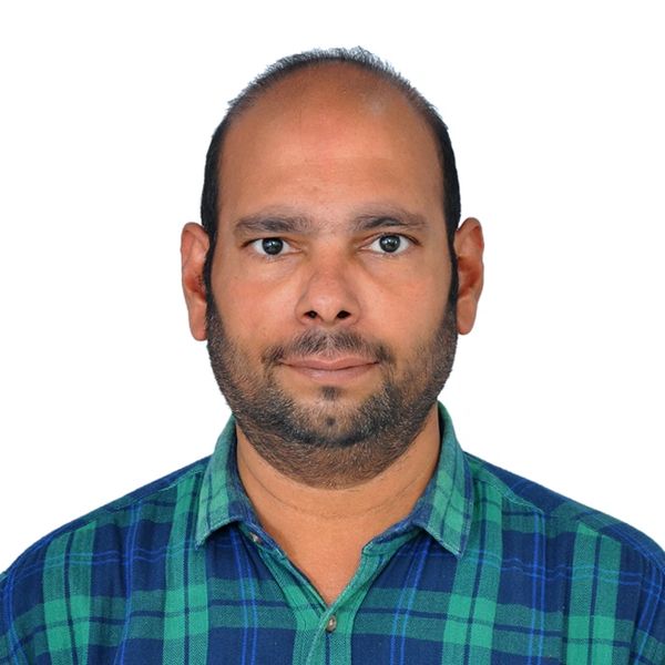 Man with a trimmed beard wearing a green and blue checkered shirt.