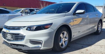 Silver Chevrolet Malibu parked outdoors with visible dent on the door.