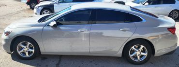 Silver Chevrolet Malibu sedan side view in parking lot.