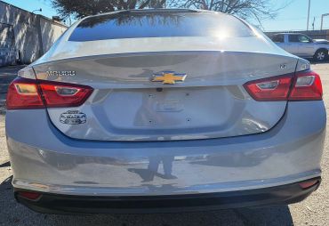 Rear view of a silver Chevrolet Malibu with dealership sticker and no license plate.