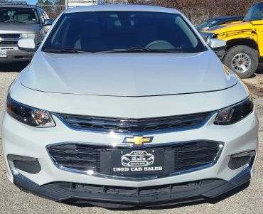 Front view of a white Chevrolet car at a used car dealership.