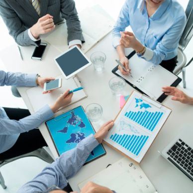 Business meeting with charts and digital devices on the table.
