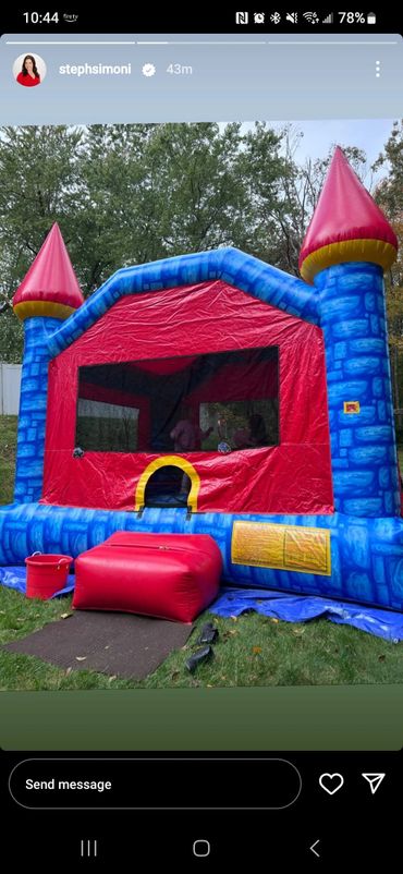 Colorful inflatable bounce house shaped like a castle in a backyard.