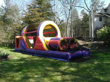 A colorful inflatable obstacle course set up on a grassy lawn.