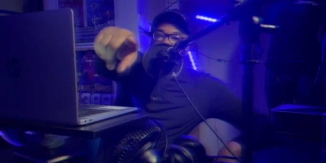 Person pointing towards the camera in a blue-lit recording studio.