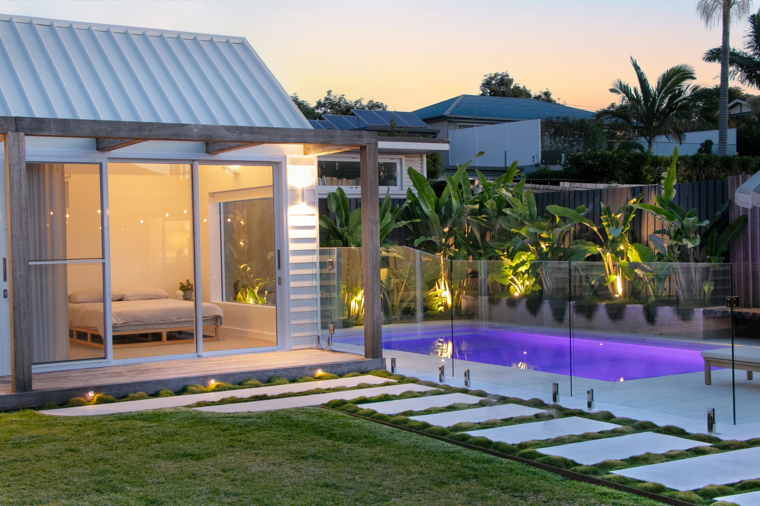 Modern house with lit pool and cozy interior at dusk.