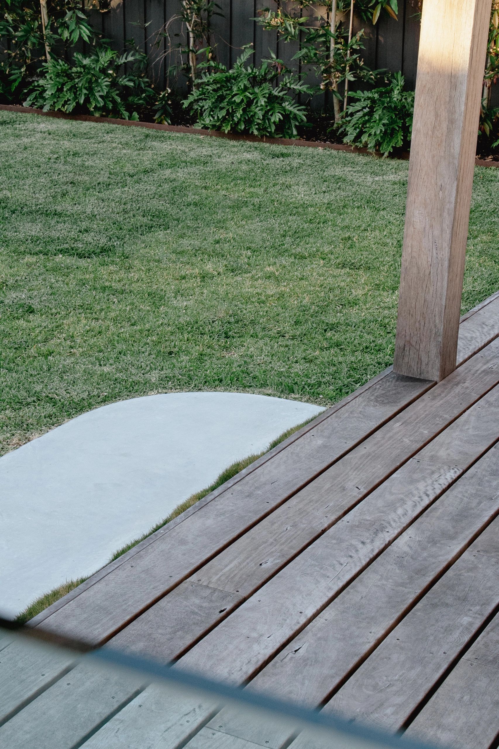 Well-maintained garden with wooden patio and curved concrete path.