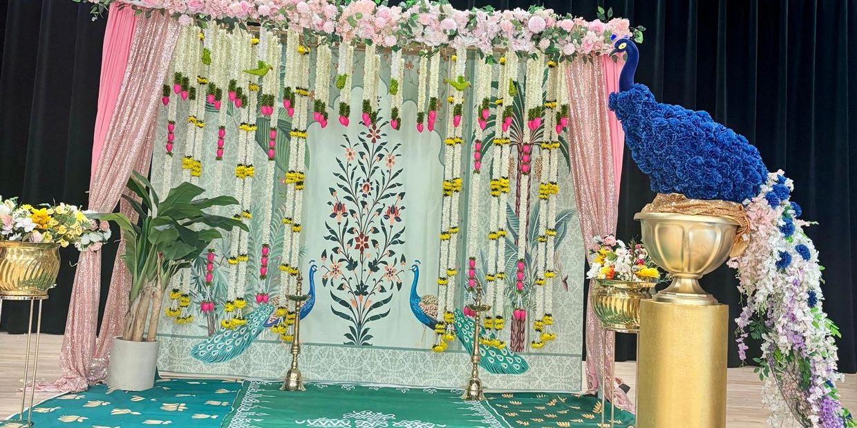 Elegant floral stage setup with peacock motifs and vibrant hanging flowers.