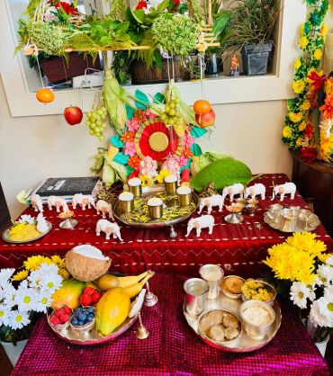 Colorful traditional Indian pooja setup with fruits, flowers, and offerings on a decorated altar.