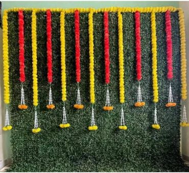 Decorative floral backdrop with marigold garlands and hanging silver embellishments.