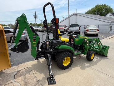 Green John Deere compact tractor with backhoe attachment.