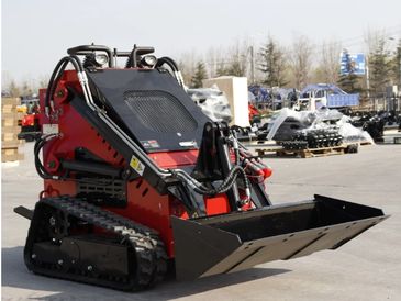 Compact track loader with bucket attachment outdoors.