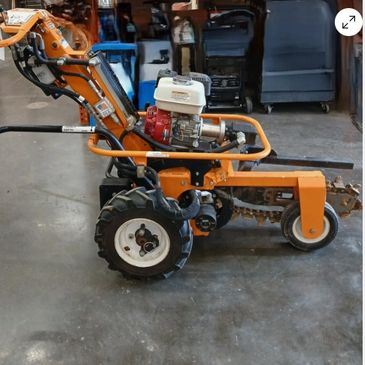 Orange trencher machine with engine and tires indoors.