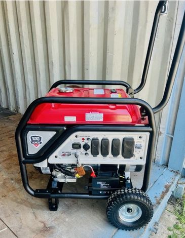A portable red and black generator with wheels.