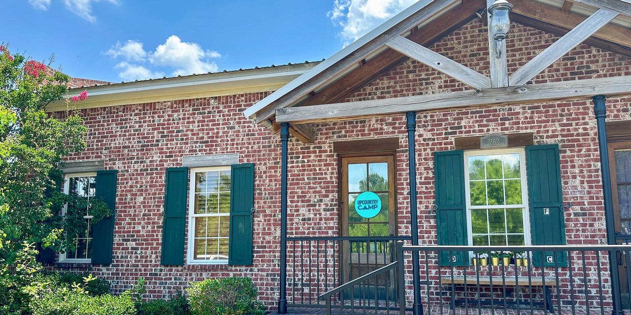 Brick building with green shutters and a wooden door.