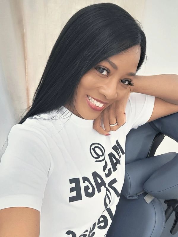 Smiling woman with long black hair wearing a white graphic T-shirt.