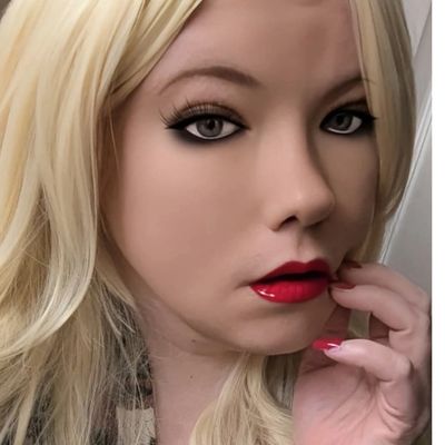Close-up portrait of a blonde woman with bold makeup and red lipstick.
