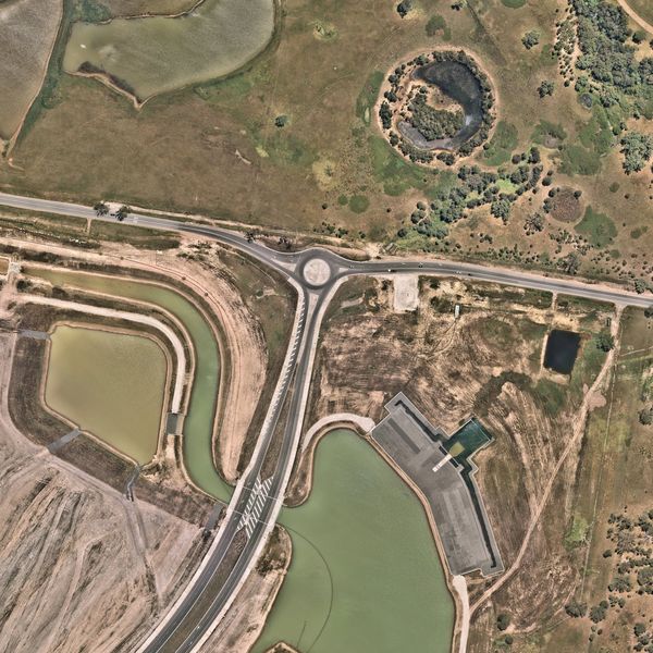 Aerial view of a rural area with roads, roundabout, and water bodies.