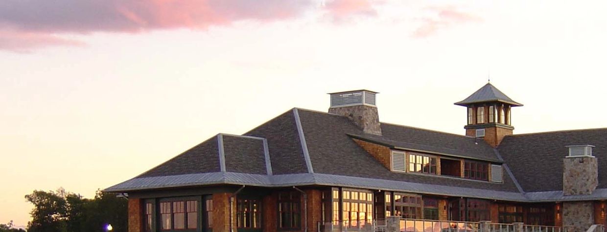Large rustic-style building at sunset with reflective windows and a small tower.
