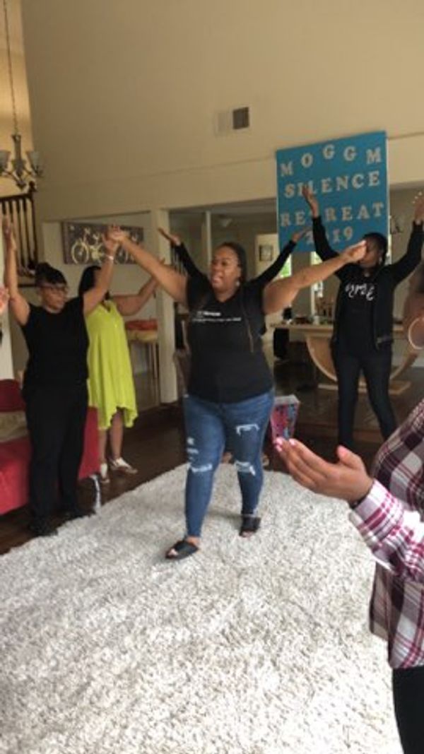 Group of women with arms raised in a lively indoor gathering.