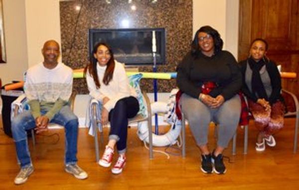 Four people sitting on chairs in a cozy indoor setting.