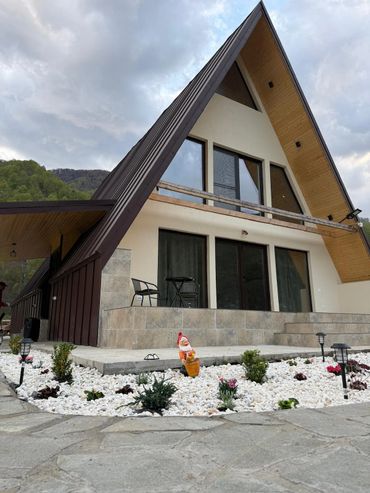 Modern A-frame house with a stone patio and garden gnome.