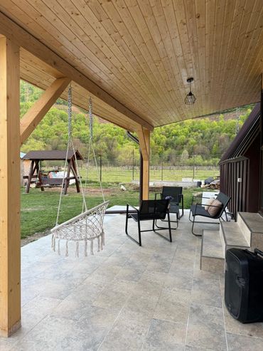Cozy outdoor patio with swing and seating overlooking green landscape.