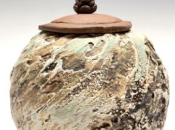 A rustic, textured ceramic jar with a lid and decorative knob.