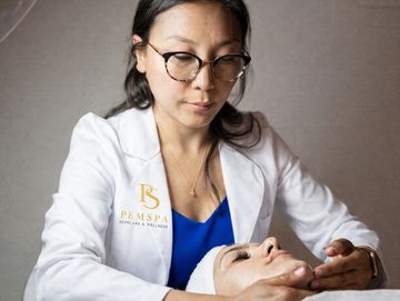 PemSpa Founding Esthetician in a white lab coat providing vitamin c brightening facial on a client