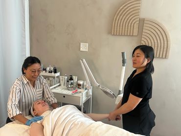 Two estheticians at pemspa skincare and massage providing treatment to a client in a beautiful room