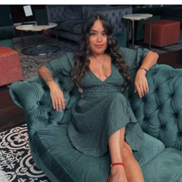 Woman sitting confidently on a teal sofa.