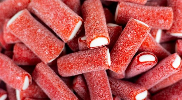Close-up of red and white candy sticks coated in sugar.