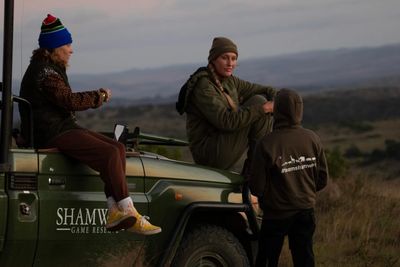 Trois personnes discutant au milieu de la savane pendant le coucher du soleil