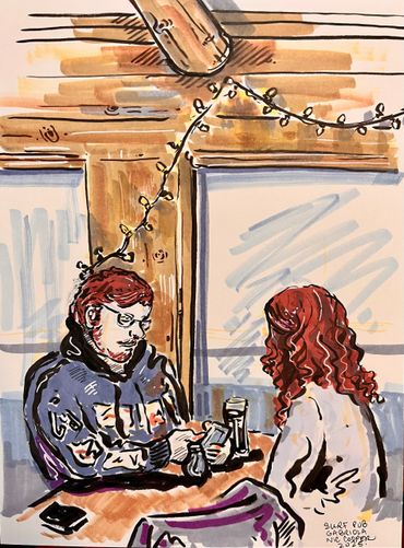 Two people sit at a table in a cozy pub with string lights above.