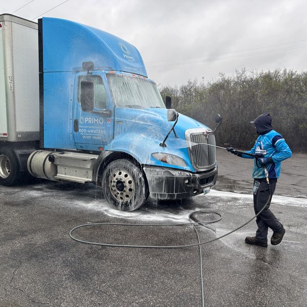 A worker applying soap to a semi tractor during his fleet washing process